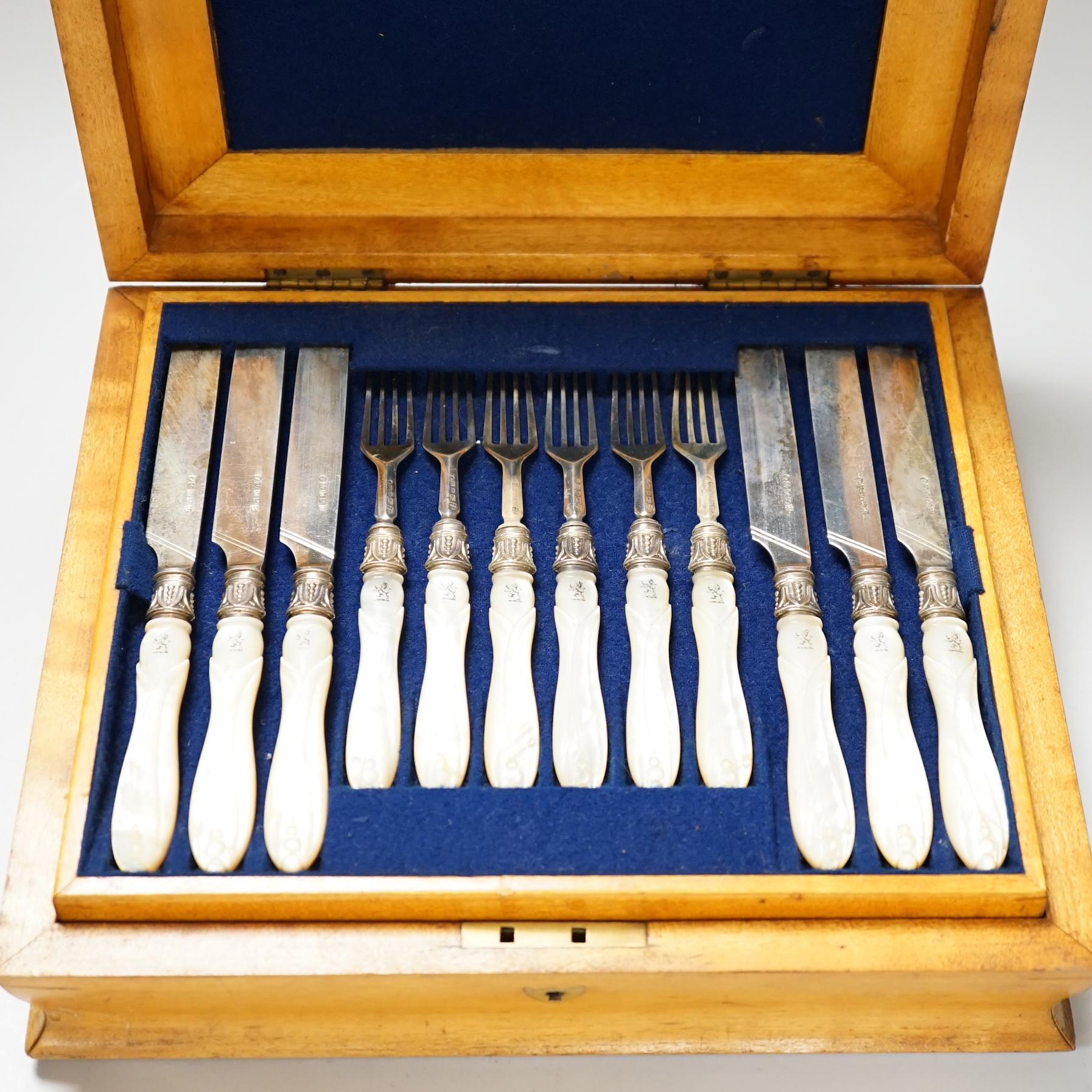 A Victorian cased set of twelve pairs of silver dessert knives and forks, with crested carved mother of pearl handles, Sheffield 1855